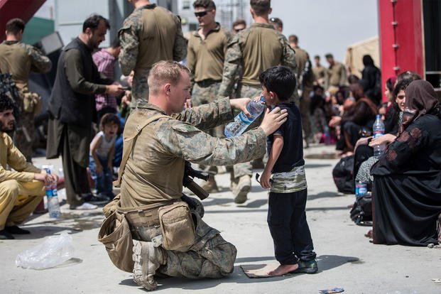 U.S. Marine Corps Marines from the 24th Marine Expeditionary Unit and U.S. Navy Corpsmen with Special Purpose MAGTF - Crisis Response - Central Command provide fresh water to children at Hamid Karzai International Airport in Kabul, Afghanistan.