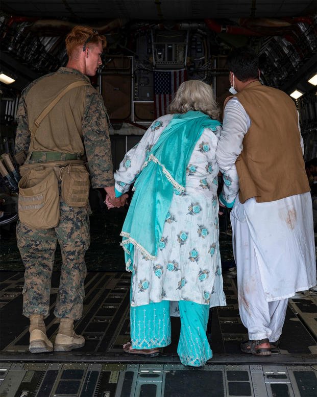 U.S. Marine Corps Marines and United States Air Force airmen lead Afghan citizens.