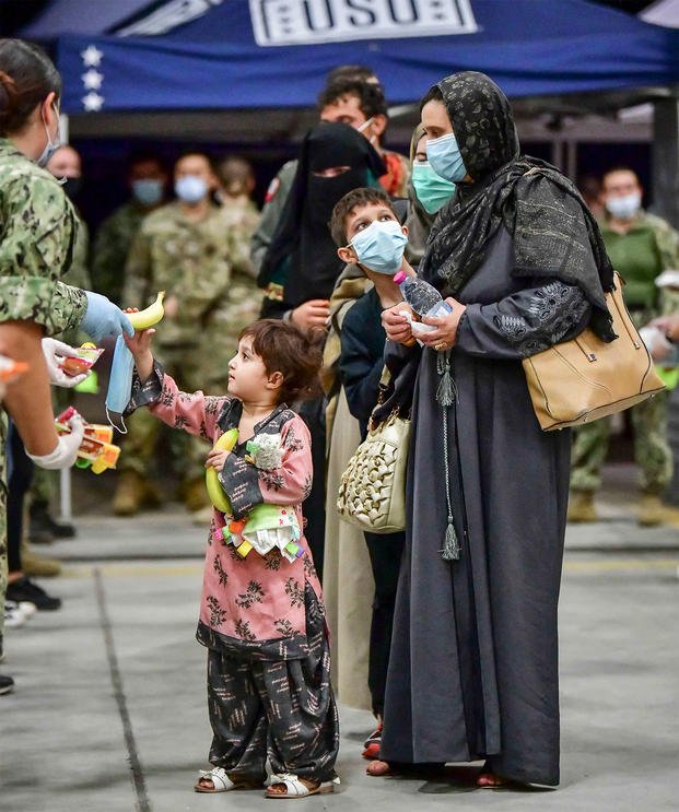 A family of Afghan evacuees receive food and masks.