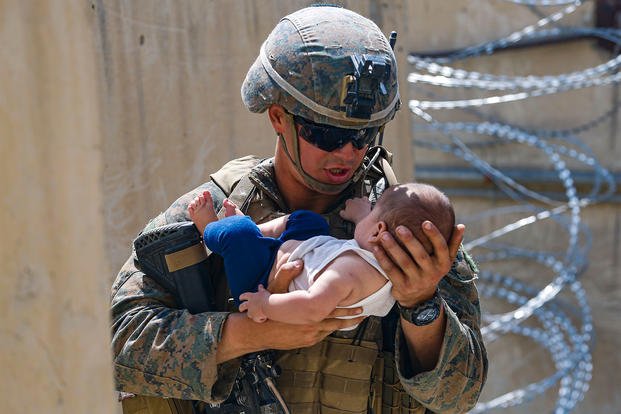 A U.S. Marine assigned to 24th Marine Expeditionary Unit (MEU) comforts an infant.