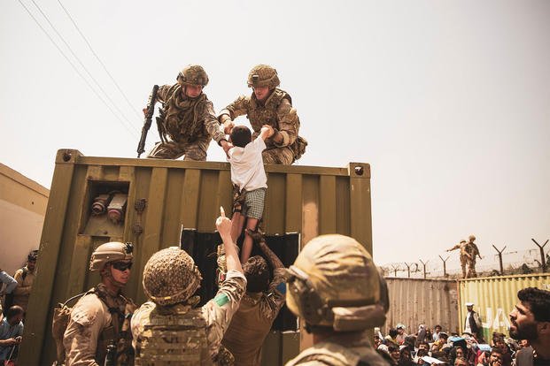 UK coalition forces, Turkish coalition forces, and U.S. Marines assist a child.