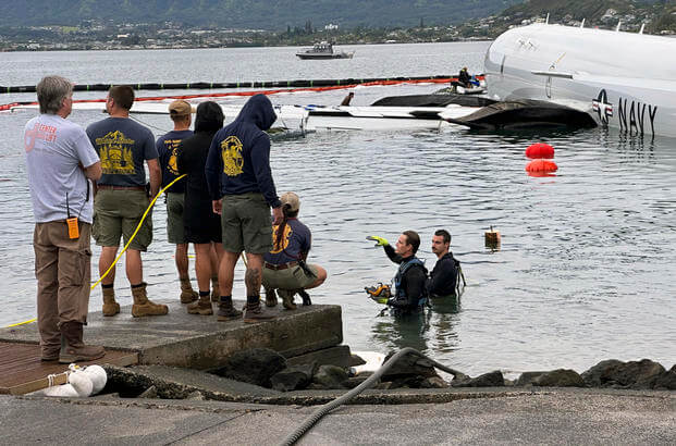 Contractors place inflatable bags under a U.S. Navy P-8A in Kaneohe Bay, Hawaii.