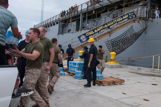 Sailors and Marines load cases of water onto the amphibious dock landing ship USS Ashland (LSD 48) in preparation for the ship getting underway to deploy to Saipan. (U.S. Navy photo by Leah Eclavea/Released)