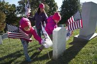 Coast Guard Lt. Cmdr. Melissa Ransom and her daughters participate in the annual Flags Across America event at Arlington National Cemetery in Arlington, Va., Nov. 5, 2016.
