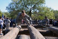 Chaplain (Capt.) MAn airman crawls across an obstacle during a team-building exercise.