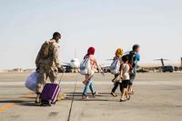 U.S. Marine takes an Afghan evacuees’ luggage to the plane at Al Udeid