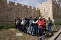 Palestinian Muslims pray outside of the walls of the Old City of Jerusalem